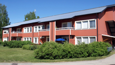 Lägenhetshus i två våningar med träfasad.