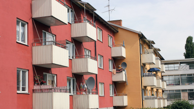 Gult och rött flerbostadshus i tre våningar. Samtliga lägenheter har vita balkonger.