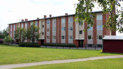 Översikt bostadsområde. Gröna gräsmattor i förgrunden och flerbostadshus i tre våningar och rött tegel.