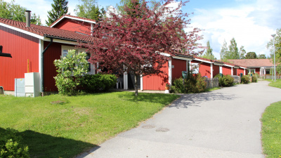 Radhuslänga i rött trä med brunt tegeltak. Vissa delar av lägenheterna är i två plan.