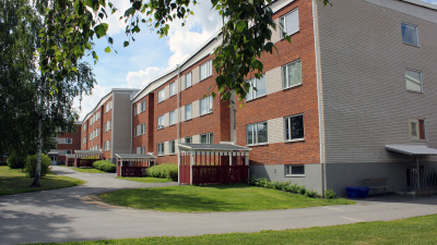 Rött och vitt tegelhus i tre våningar. Röda cykelbodar vid entréerna.