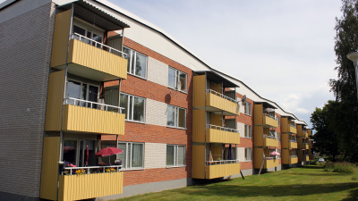 Rött tegelhus i tre våningar med gula balkonger.