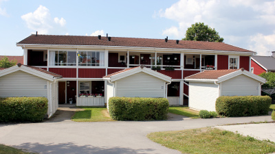 Översiktsbild över innergård på bostadsområdet Mästaren. Flerbostadshusen har två våningar med egna ingångar och fristående förråd i små hus framför entréerna.