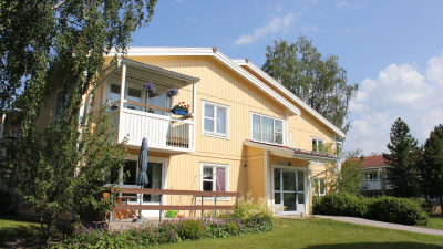 Lägenhetshus i två våningar med träfasad.