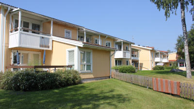 Lägenhetshus i två våningar med träfasad.