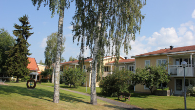 Lägenhetshus i två våningar med träfasad.