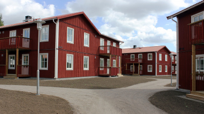Bild på röda trähus med lägenheter i två våningar och egen ingång ifrån loftgång.