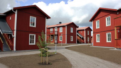 Bild på röda trähus med lägenheter i två våningar och egen ingång ifrån loftgång.