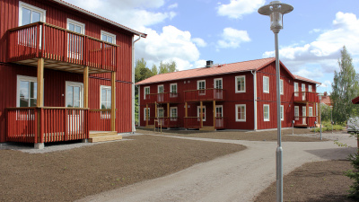 Översitsbild av bostadområdet Säversta. Röda trähus i två våningar med balkonger som har träräcken. Gatlampa i förgrunden.