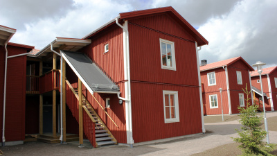 Bild på röda trähus med lägenheter i två våningar och egen ingång ifrån loftgång.
