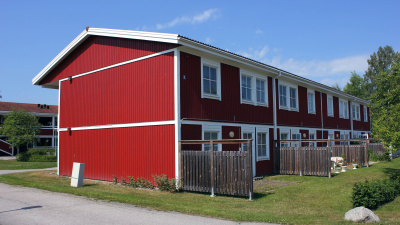 Tvåvånings lägenhetshus med röd träfasad.