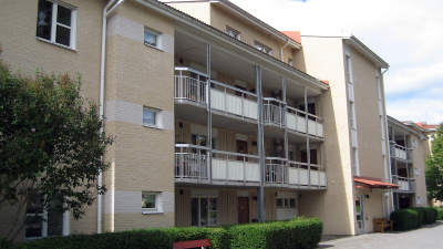 Lägenhetshus i tre våningar. åningar med inglasade balkonger och uteplatser i markplan.