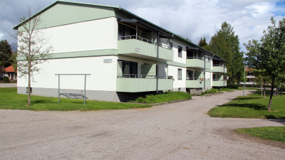 Flerbostadshus med grusgångar och gräsmatta. Balkonger med ljusgröna fronter.