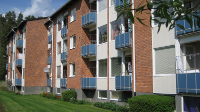 Baksidan av flerbostadshus på Södra Bäckvägen. Huset är i rött tegel i tre våningar. Samtliga lägenheter har blå balkonger.