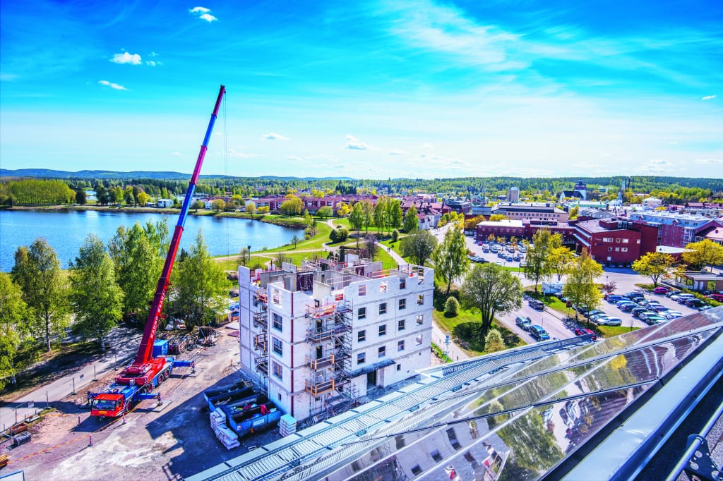Bild på uppbyggnad av hyreshus, byggkran och blå himmel