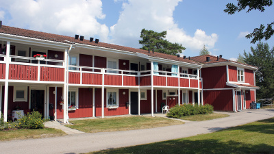 Rött flerbostadshus med egna ingångar. Andra våningen har loftgång.