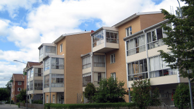 Lägenhetshus i tre våningar med inglasade balkonger och uteplatser i markplan. åningar med inglasade balkonger och uteplatser i markplan.