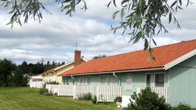 Radhuslänga i ett plan. Bilden är tagen av baksidan av radhuset. Lägenheter har uteplats med skärmväggar mellan lägenheterna. Framför huset är det gräsmatta.