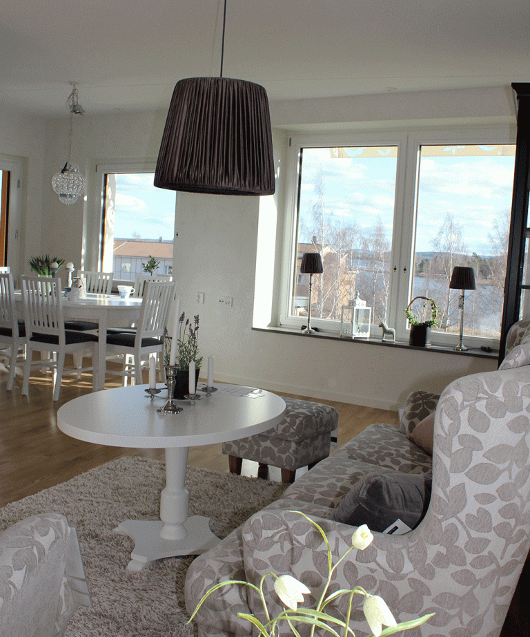 Interiörbild av ett vardagsrum med soffa och bord. I bakgrunden en matsalsgrupp.