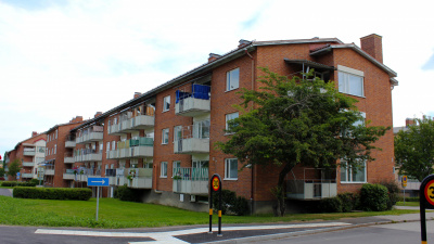 Flerbostadshus tre våningar i rött tegel och vita balkonger.