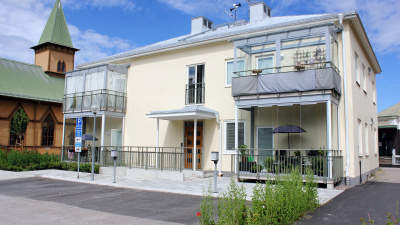 Flerbostadshus i ljusgul stenputs. Huset är i två våningar och har inglasade balkonger.