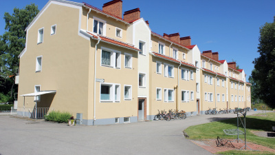 Flerbostadshus i tre våningar i gul puts. Ljusa partier vid entréerna.