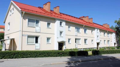 Flerbostadshus i två våningar med gul träfasad och rött tegeltak. Lägenheterna har franska balkonger.