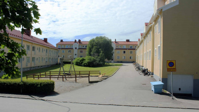 Innergård med en grön gräsmatta och en gungställning. Innergården är omsluten av tre flerbostadshus.