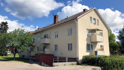 Trevånings flerbostadshus i stenputs. Bilden är tagen snett bakifrån huset. Tre garage i källaren av huset.