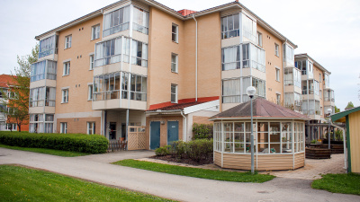 Flerbostadshus i tre våningar. Lägenheter med inglasad balkong. Framför huset står ett lusthus.